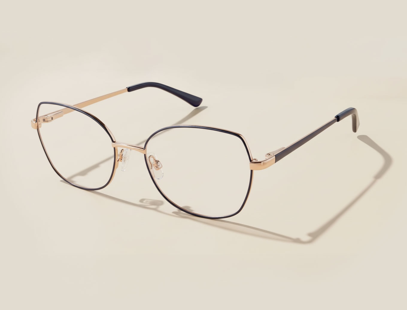 Stylish Superflex golden eyeglasses against beige background.