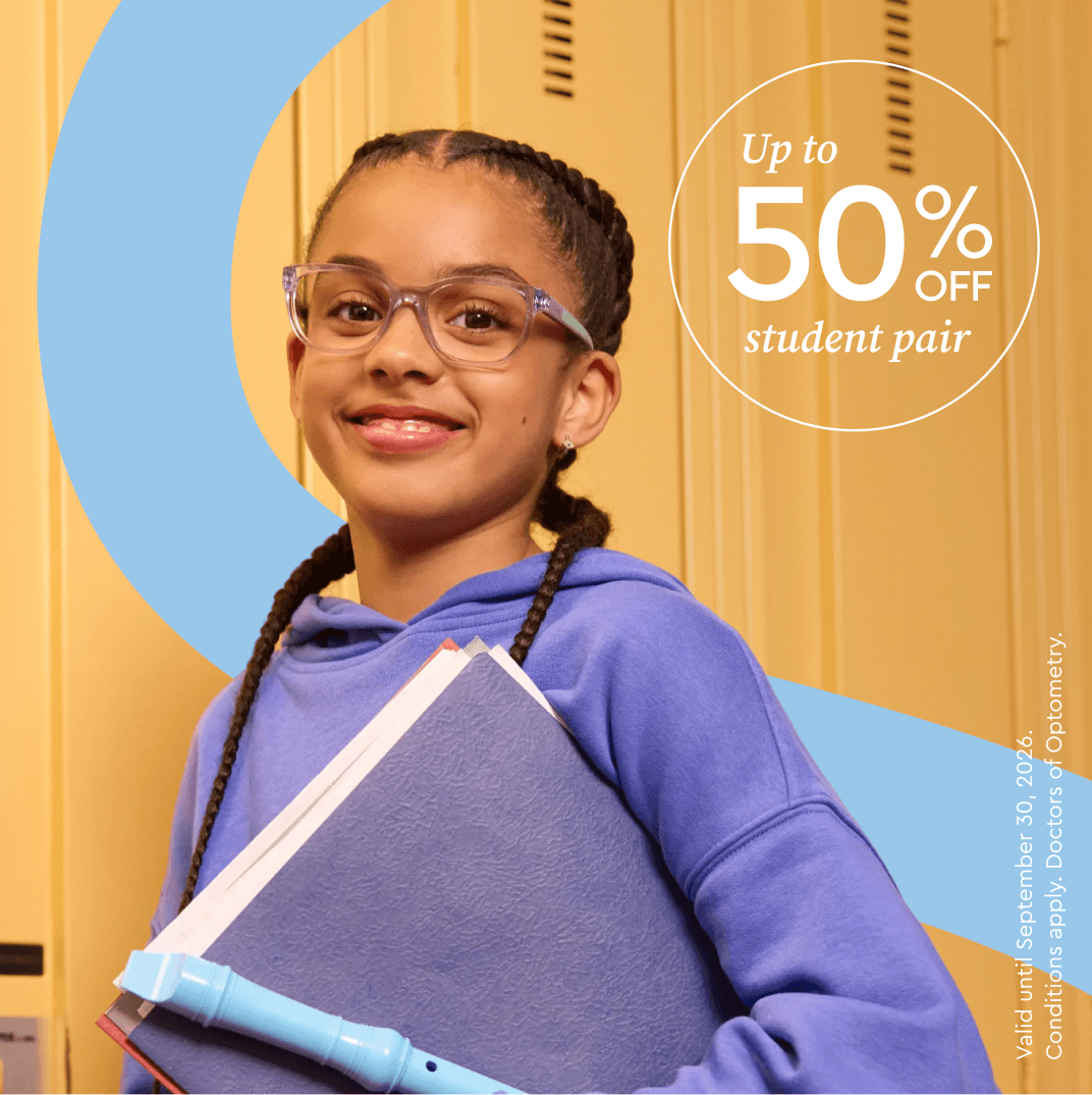 A smiling young girl with glasses and braids holds books and a flute in front of school lockers.
