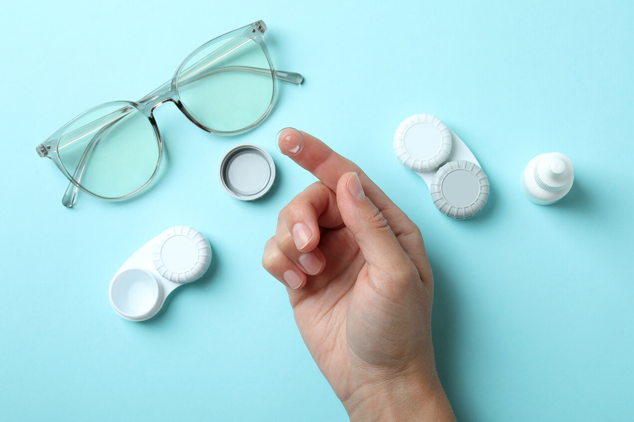 Holding contact lens with one finger, against a blue background
