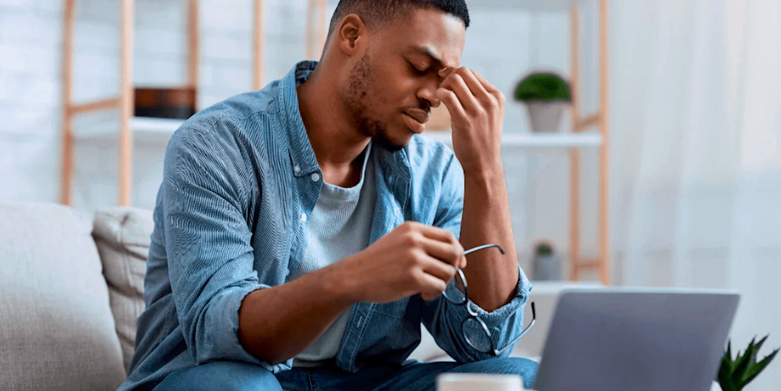 Homme se frottant les yeux en raison d’une fatigue oculaire devant un portable