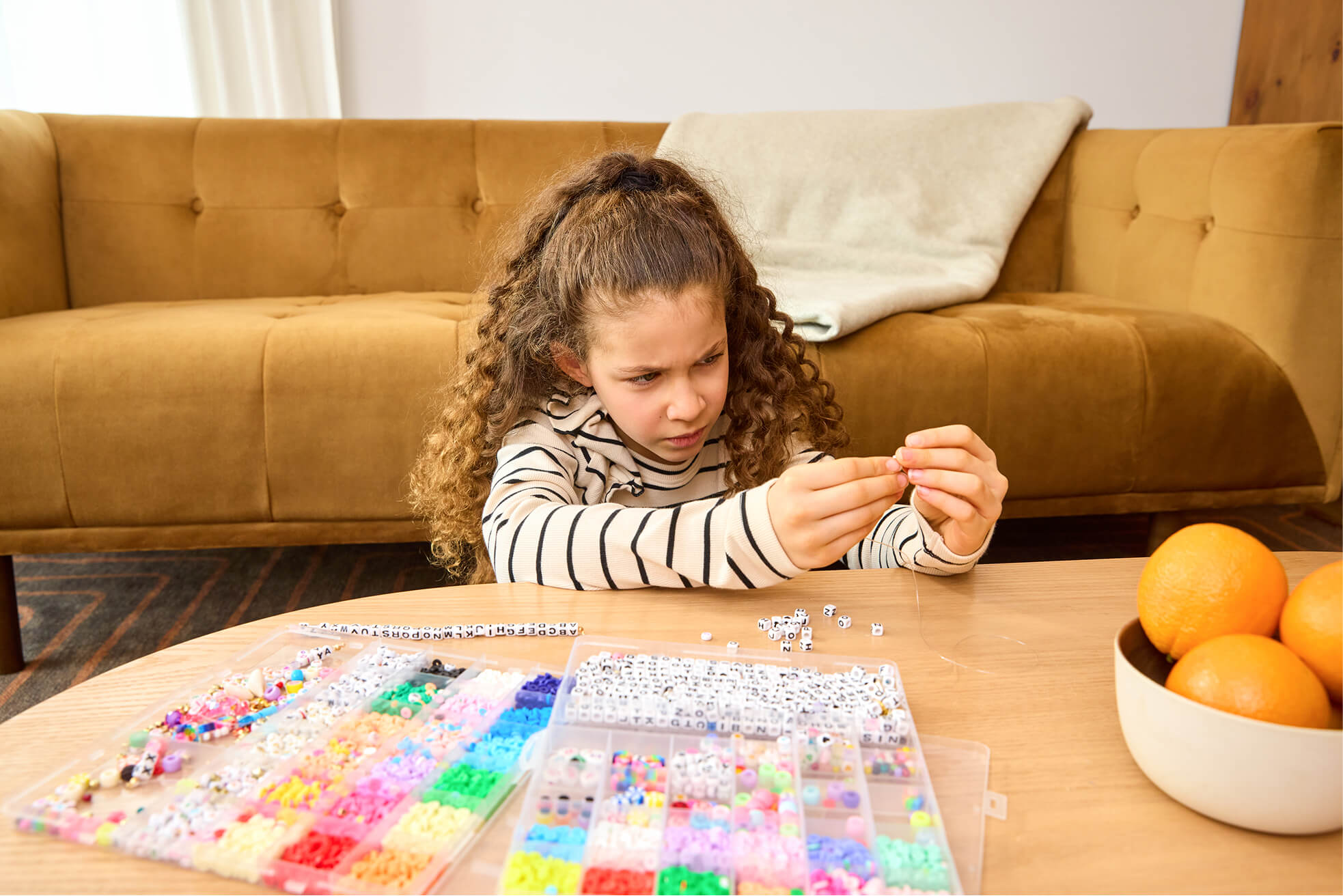 Child stringing beads at a table, having a hard time seeing the beads due to her myopia.