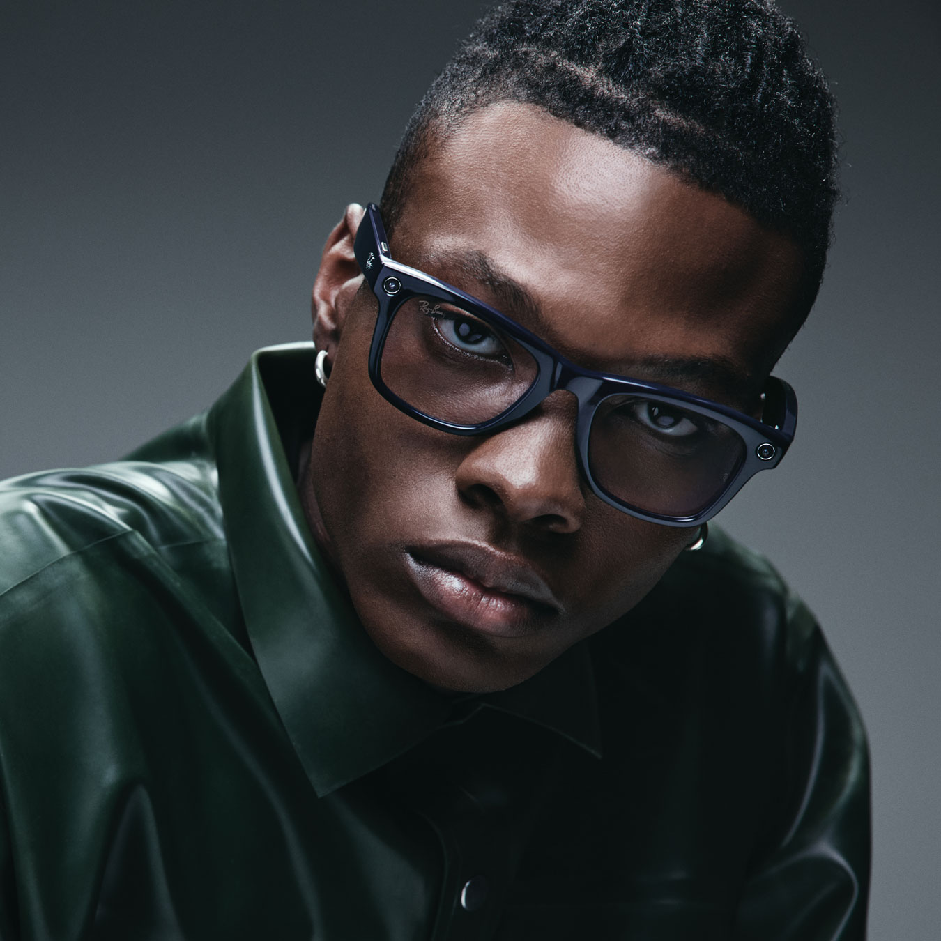 Man wearing Ray-Ban Meta black glasses, steel blue background