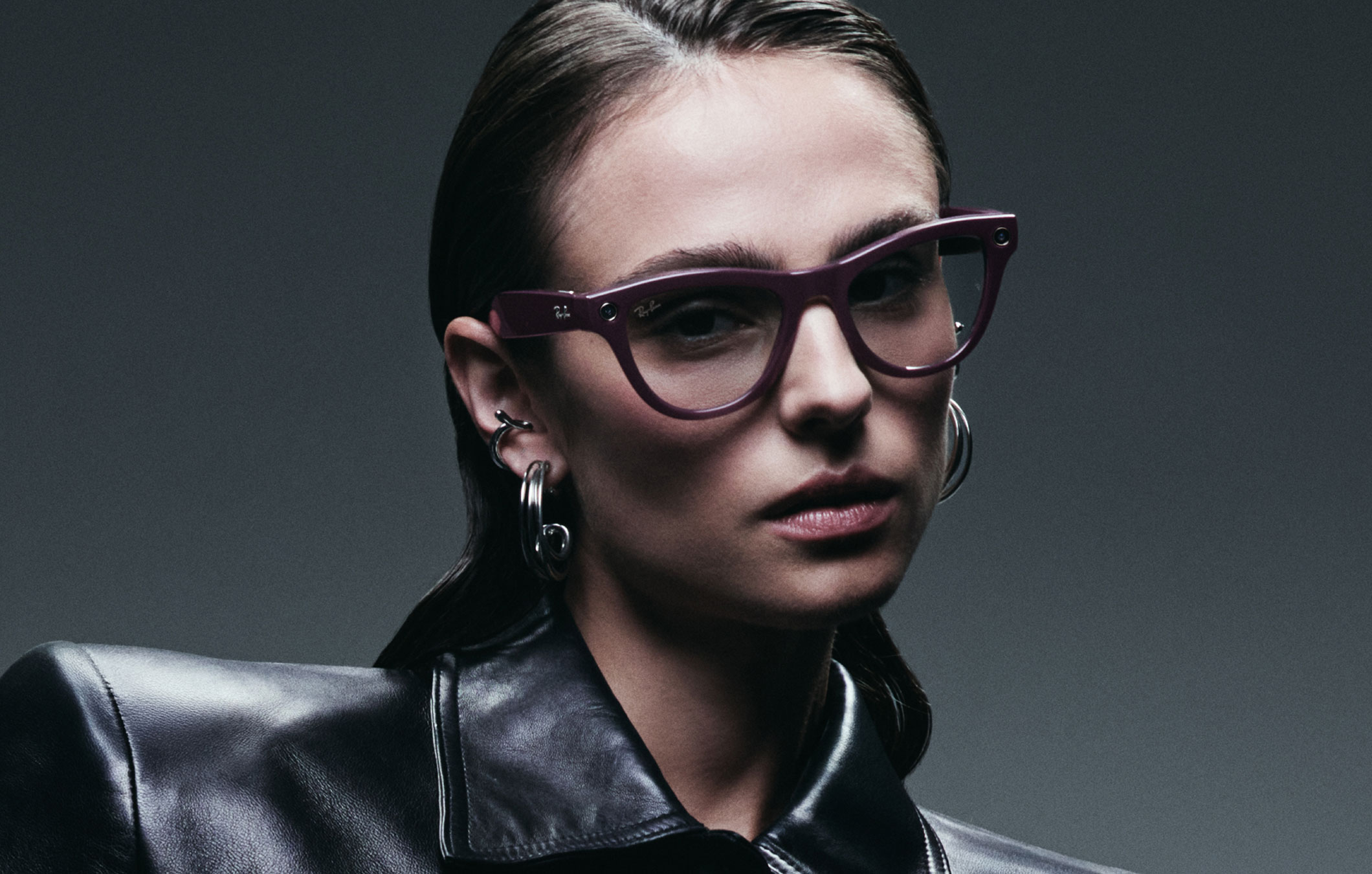 Woman wearing Ray-Ban Meta purple glasses, dark background.