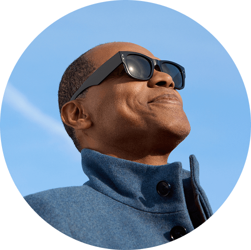 Un homme portant des lunettes de soleil et un manteau bleu regarde vers le ciel.