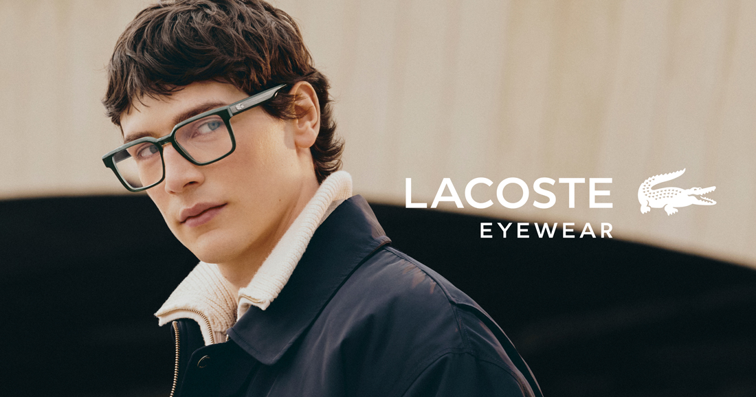 A young man with dark hair and clear blue eyes models a pair of Lacoste dark green rectangular eyeglasses.
