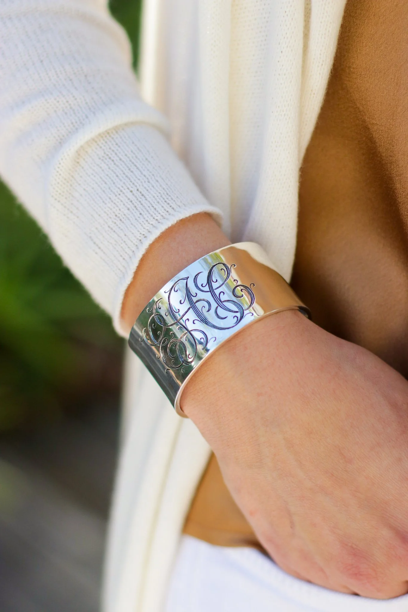 Person wearing a silver engraved bracelet on their wrist.