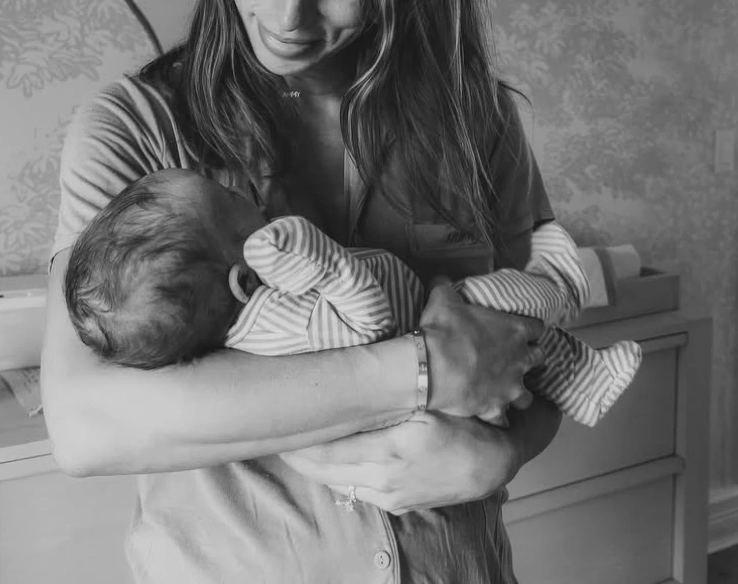 A black and white photograph of a woman cradling a newborn baby in her arms.