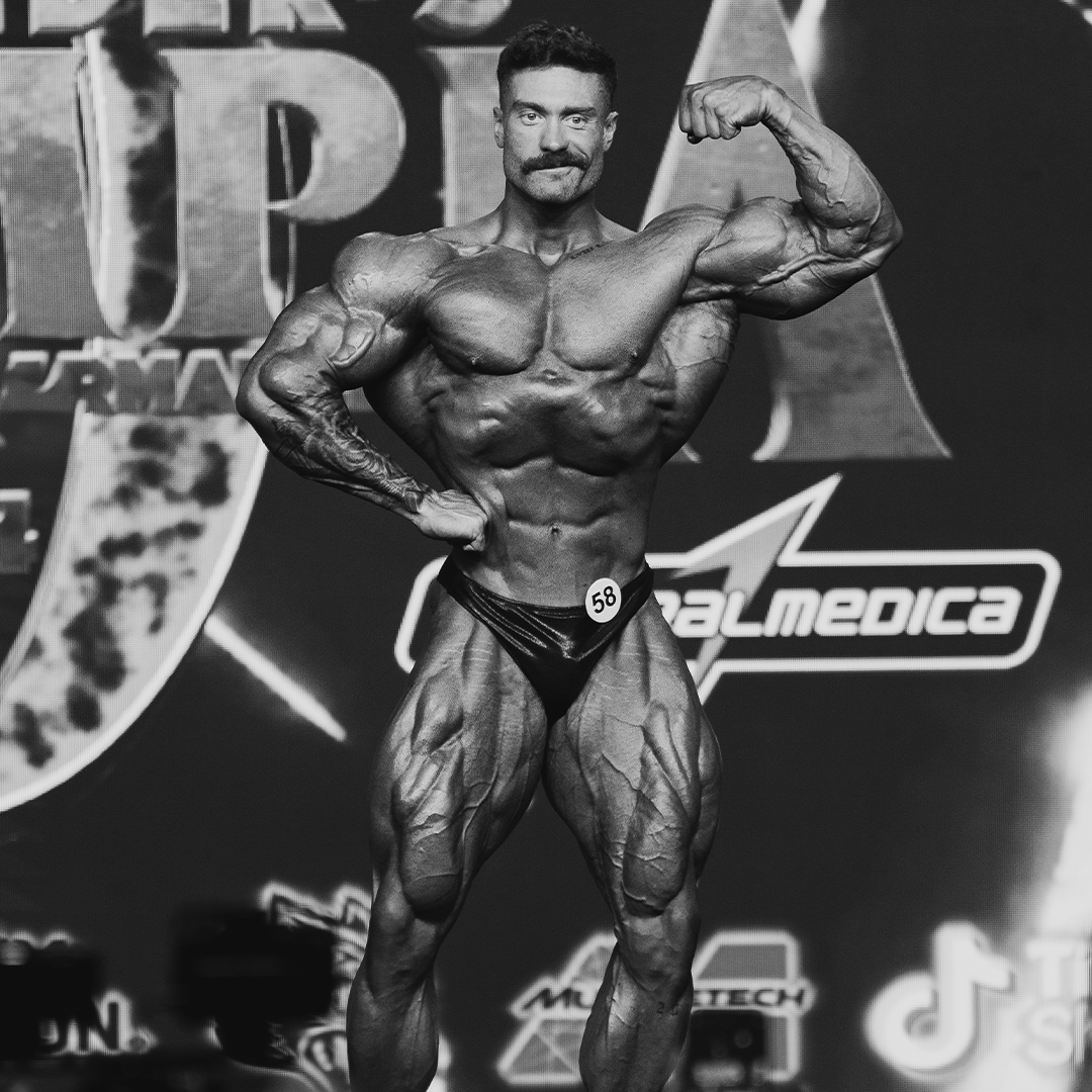 Bodybuilder posing on stage with number 58, showing muscular physique.