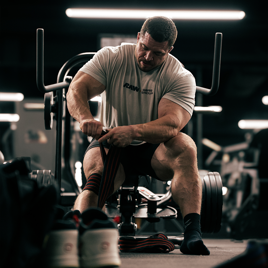 Man lifting weights on a shoulder press machine in a gym.