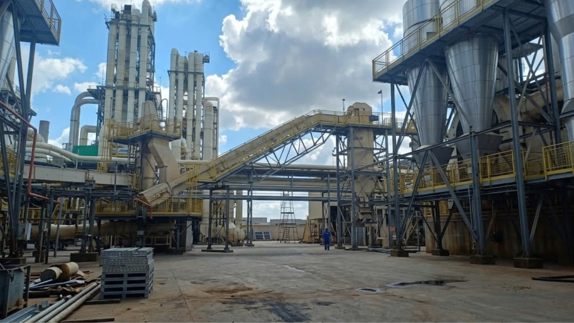 An expansive view of an industrial plant with numerous pipes, silos, and a conveyor belt.