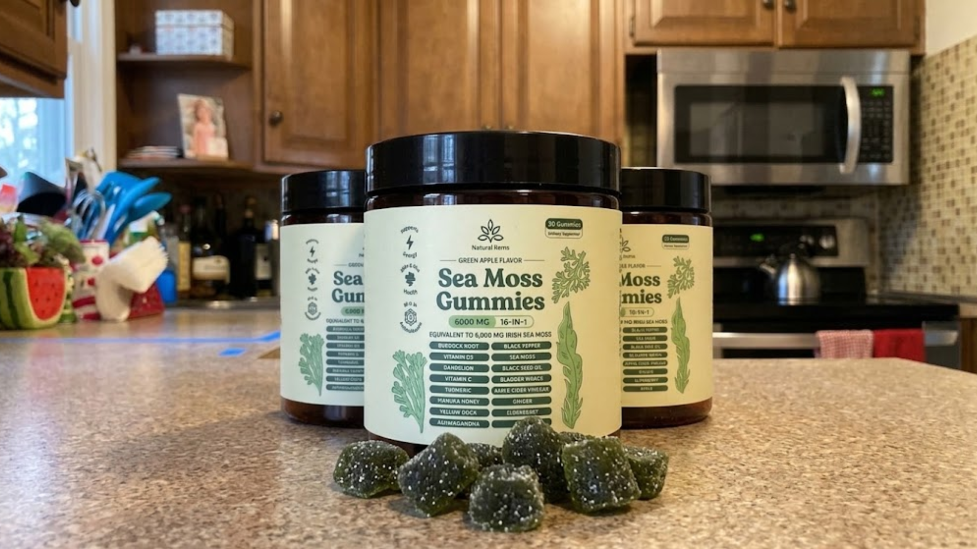 Three bottles of Sea Moss Gummies and several green gummies are displayed on a kitchen counter.