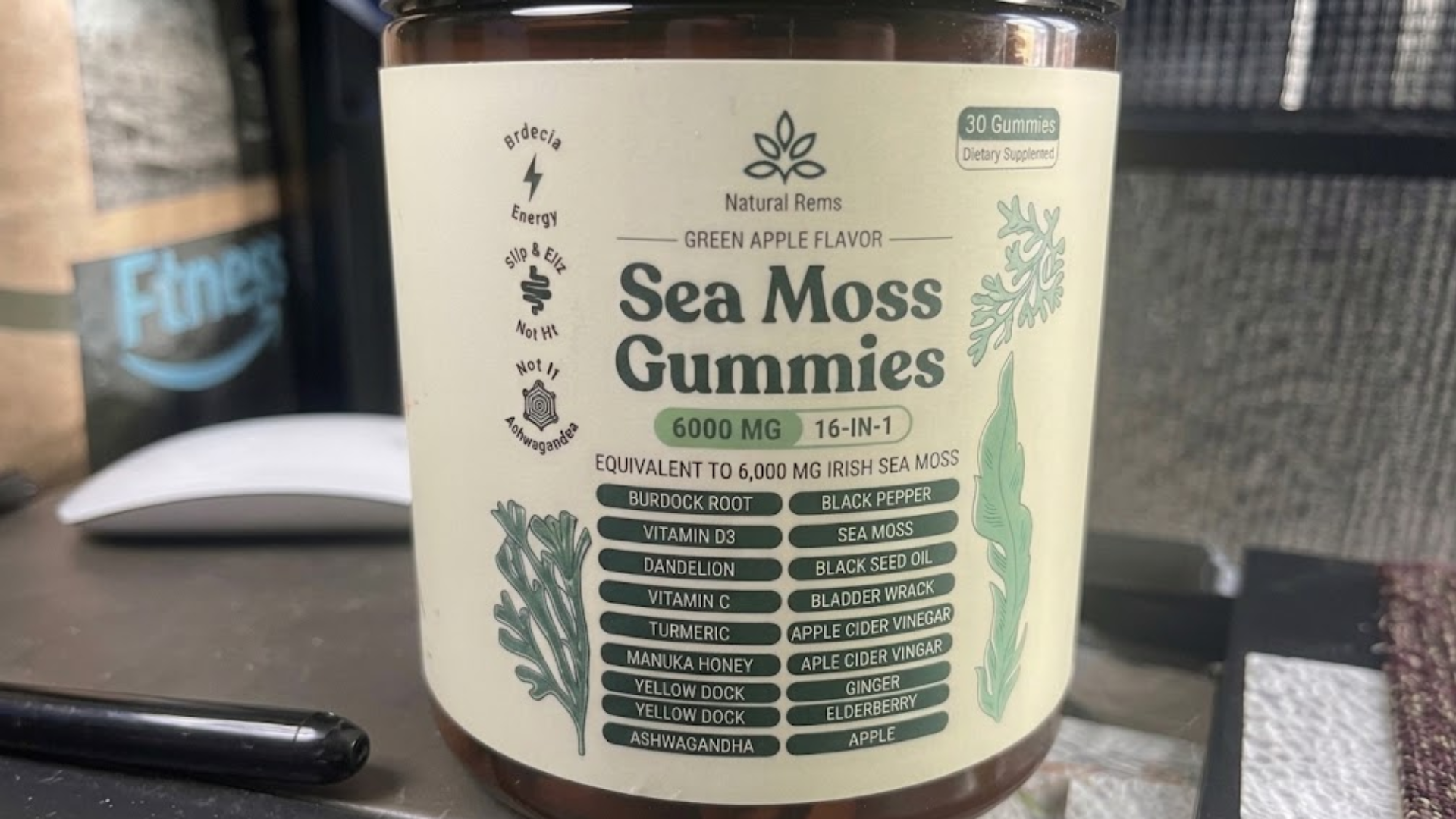 A close-up photo of a bottle of Natural Rems Sea Moss Gummies on a desk.