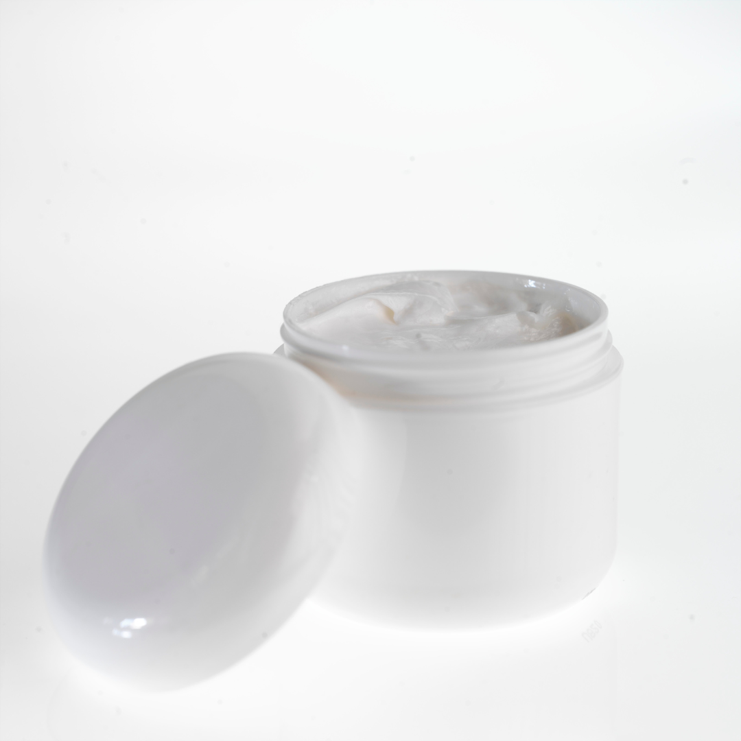 Open white jar with cream and detached lid.