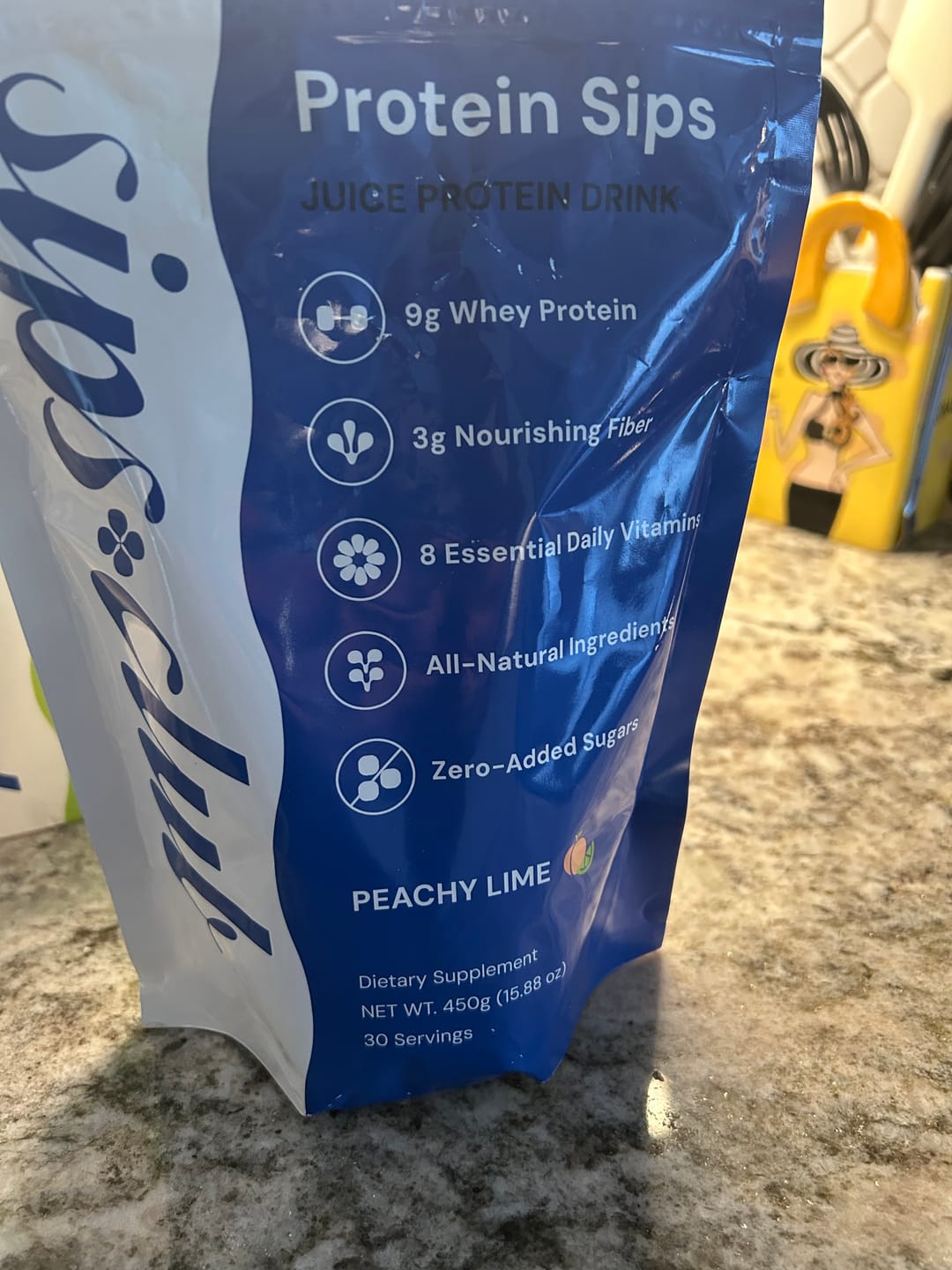 Blue package of 'Protein Sips' juice protein drink on a kitchen counter.