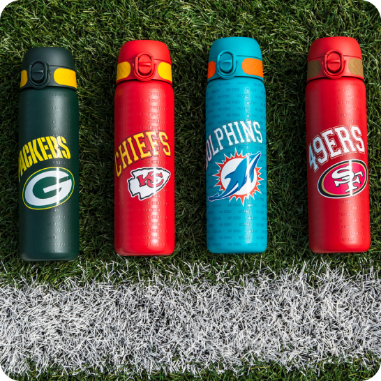 Four sports-themed water bottles on grass next to a white line.