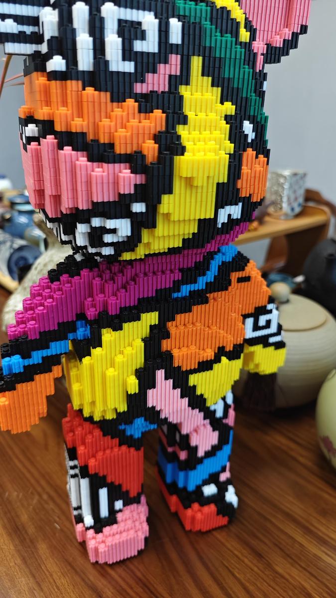 Colorful abstract figure made of vertical stacked plastic bars on a wooden surface.