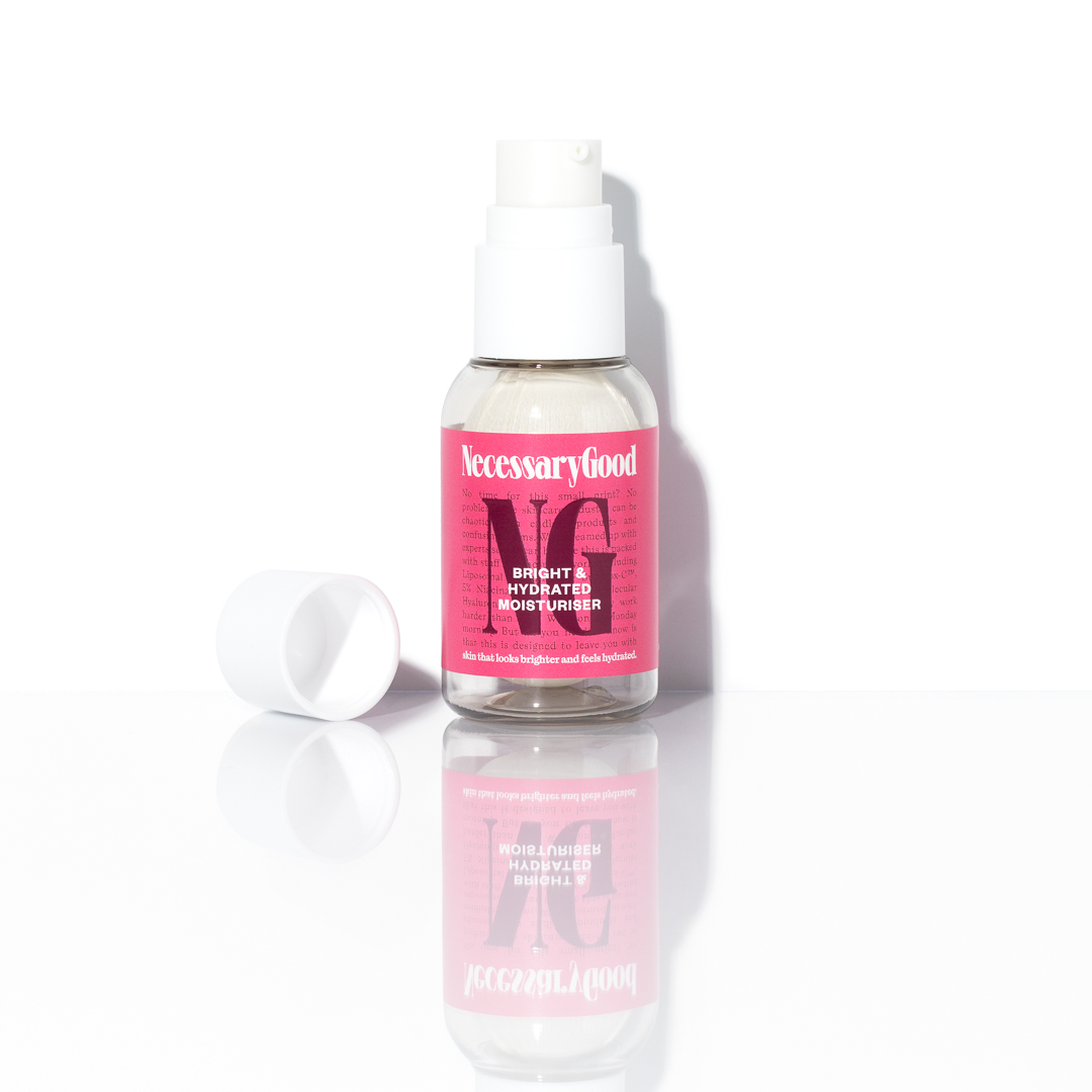 Bottle of Necessary Good moisturizer with a pink label and white cap on a reflective surface.