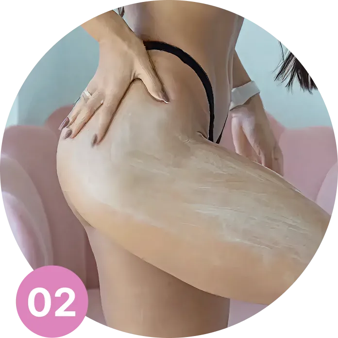 A close-up of a woman in a black thong applying a cream product to her hip and thigh.