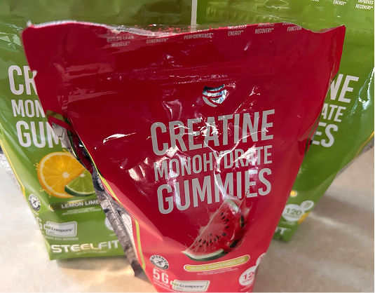 A red bag of watermelon-flavored SteelFit Creatine Monohydrate Gummies in front of a green lemon-lime bag.