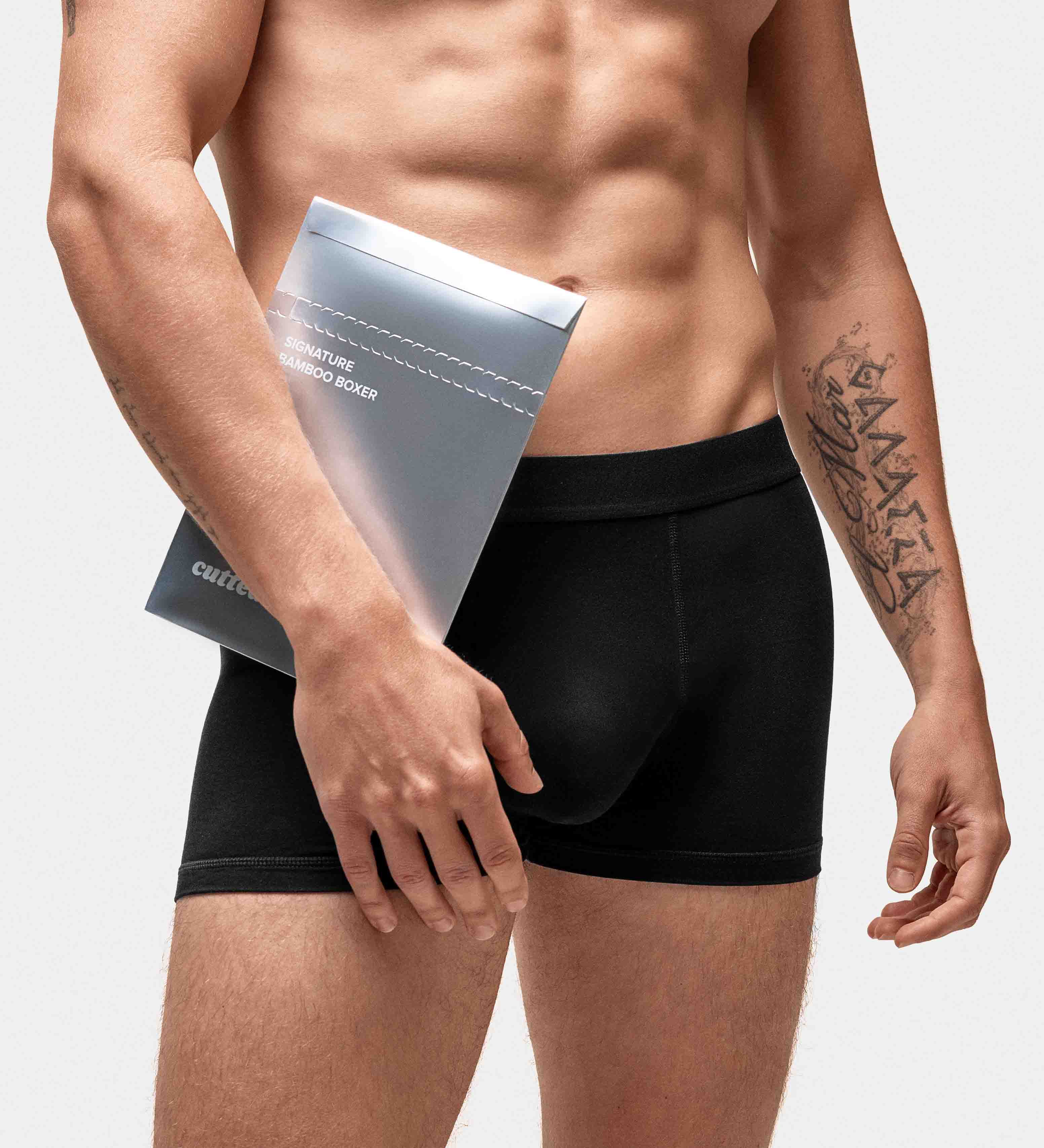 Man in black boxer briefs holding a packaging box.