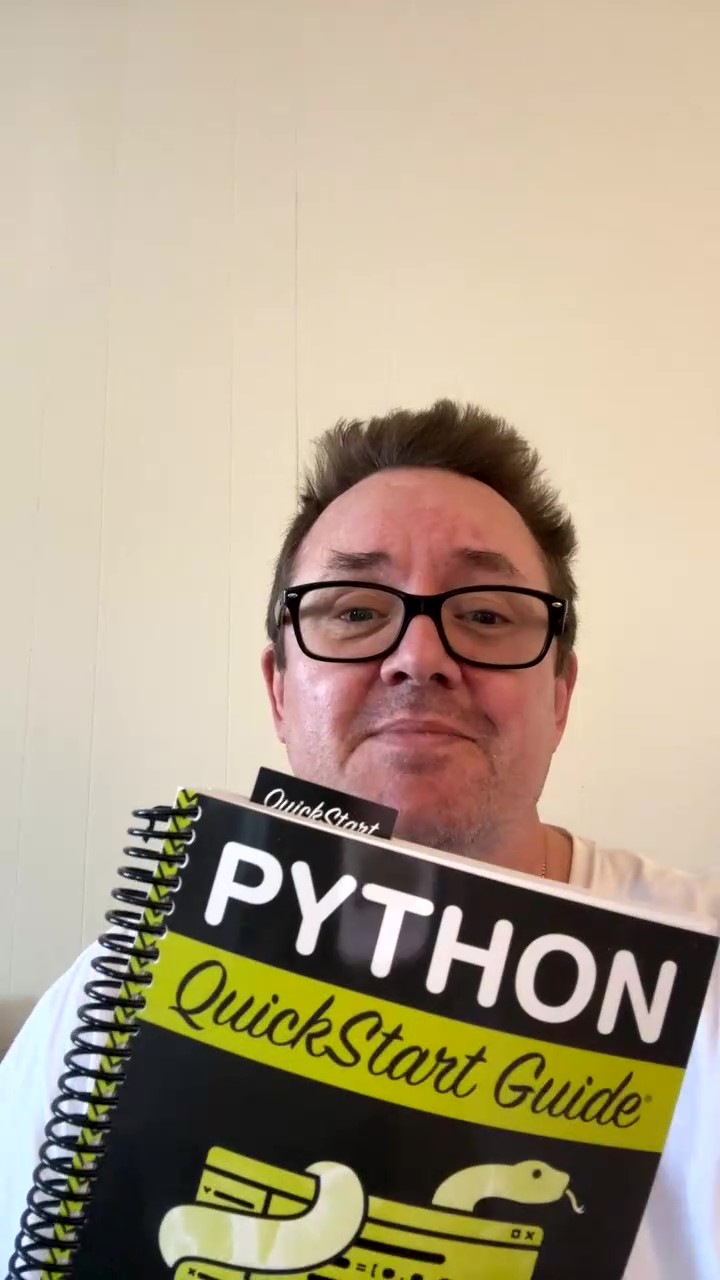 Person holding a Python QuickStart Guide book, smiling at the camera.