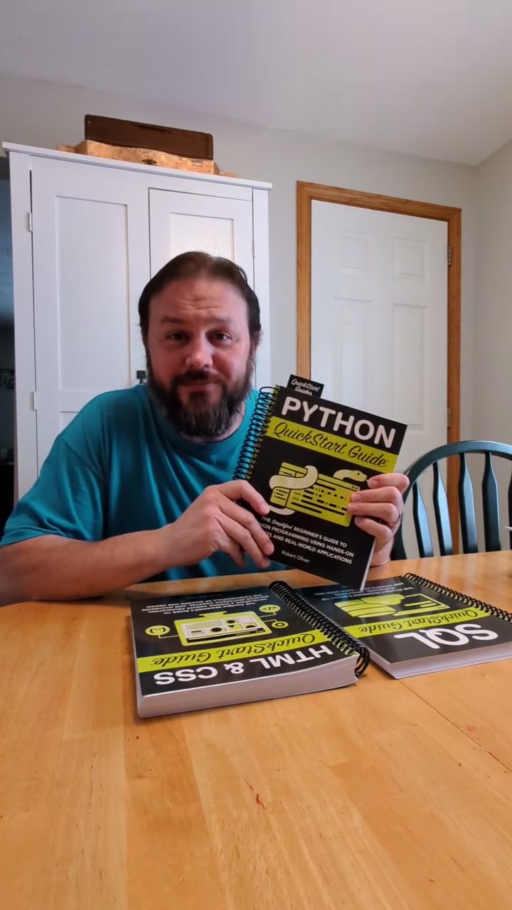 Person holding a Python QuickStart Guide book at a table.