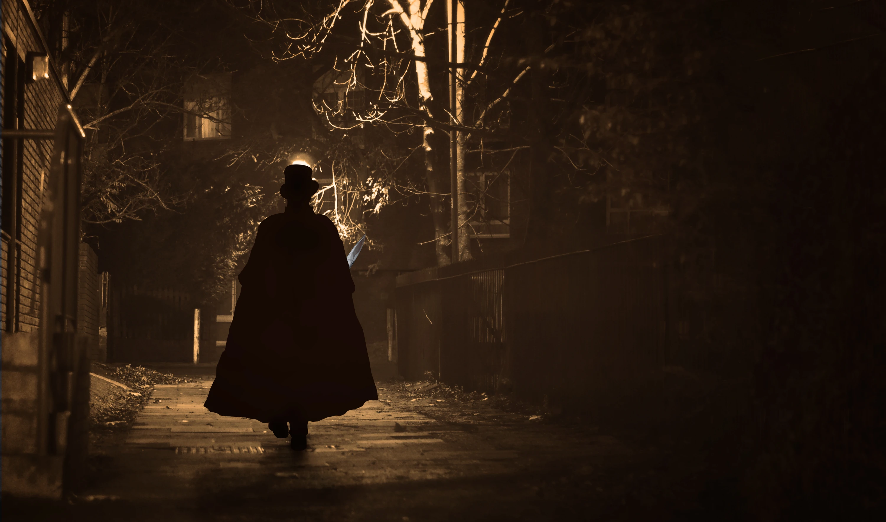 A silhouetted figure in a top hat and cloak walks down a dark, foggy street at night.