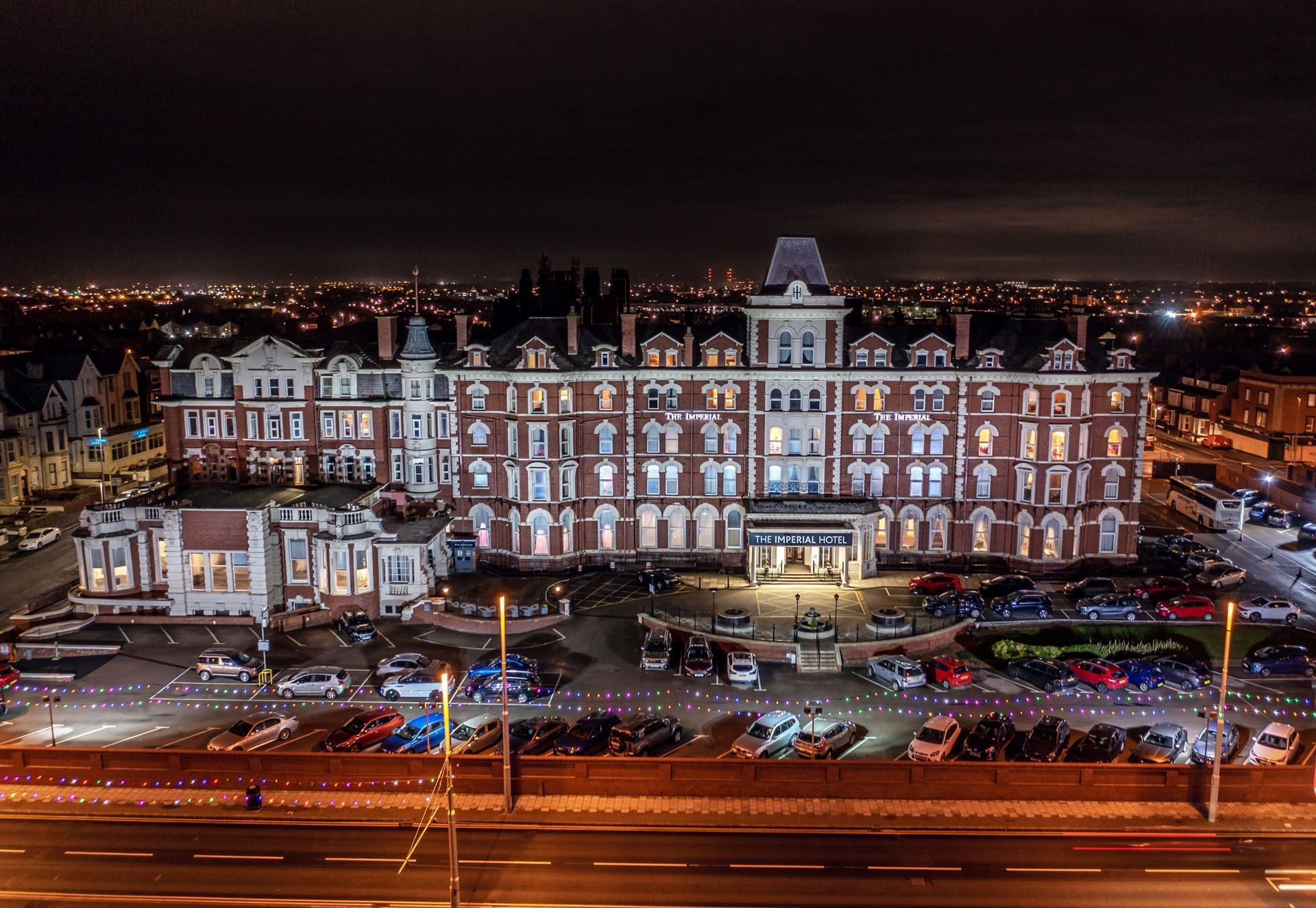 An aerial view of the grand Imperial Hotel at night, illuminated against the surrounding city lights.