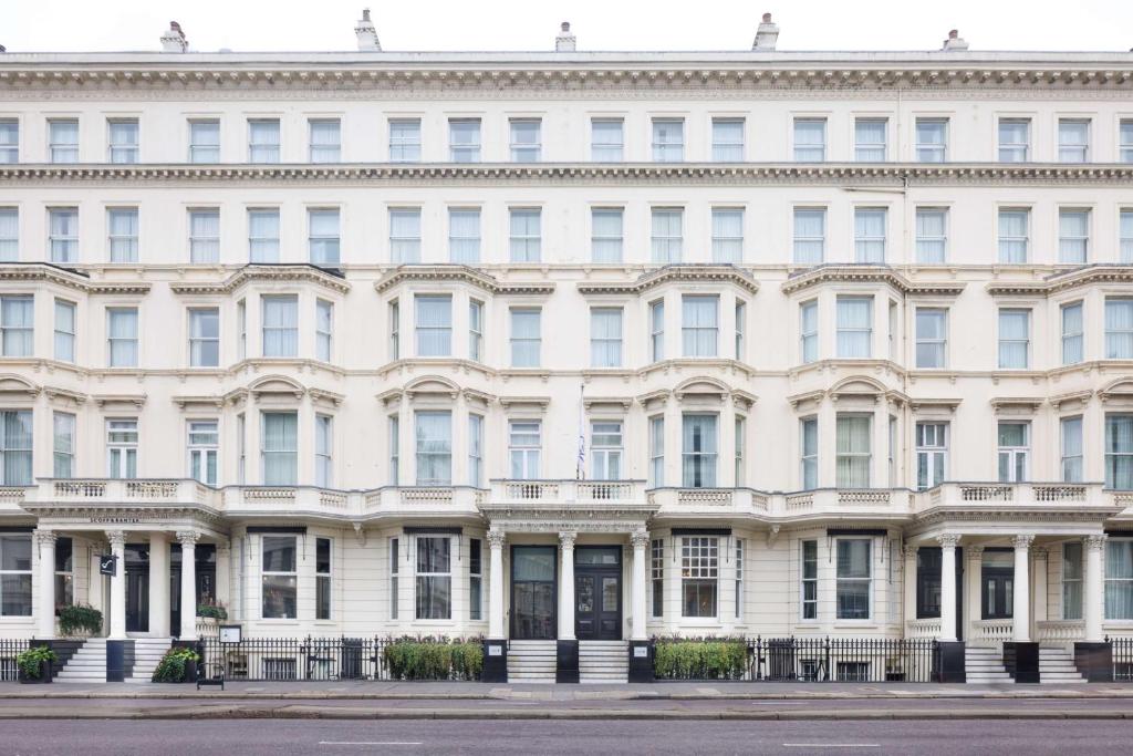 The white, symmetrical facade of a grand, multi-story building with many windows, seen from across a street.