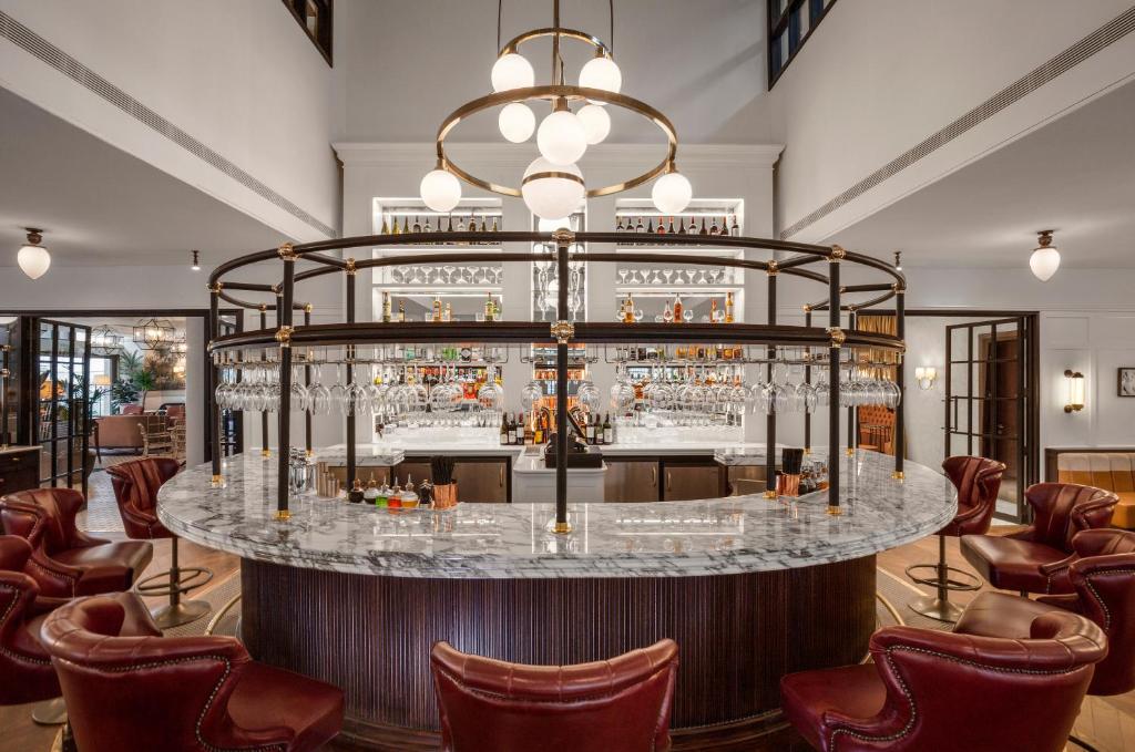 A circular marble bar with red leather chairs under a large, modern globe chandelier in an upscale restaurant.