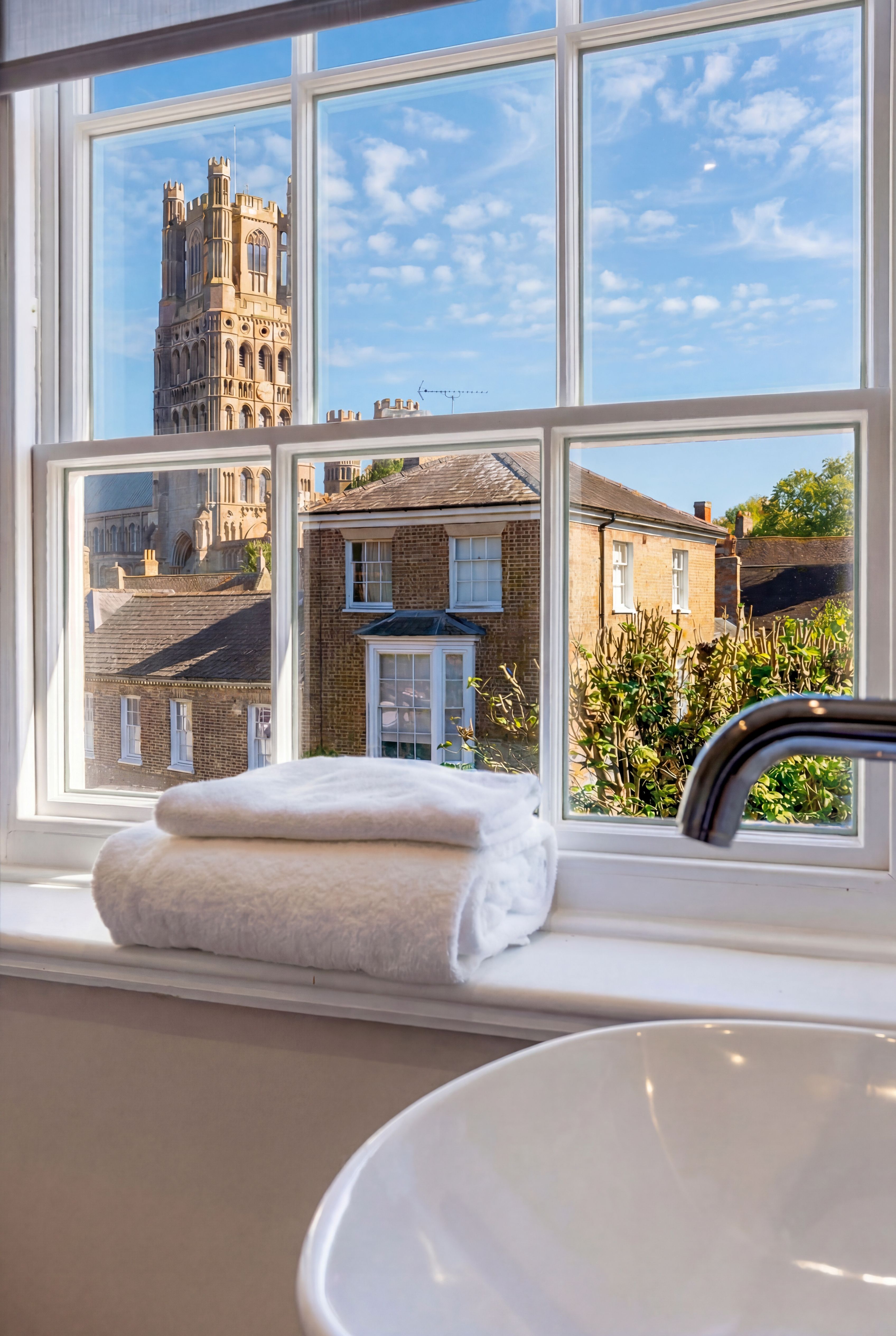A view of a historic cathedral and other buildings through a window with towels on the sill.