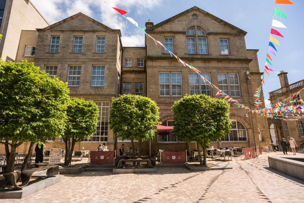 A stone building with a sunny courtyard patio, decorated with colorful bunting flags and small trees.