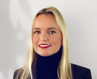 Person with long blonde hair and a black turtleneck smiling.