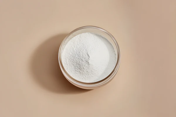 A glass bowl filled with white powder on a beige background.