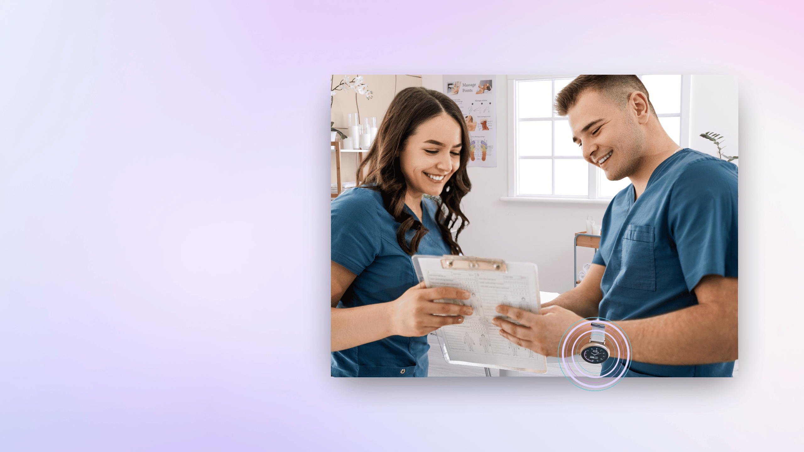 Two people in blue scrubs smiling and looking at a clipboard.