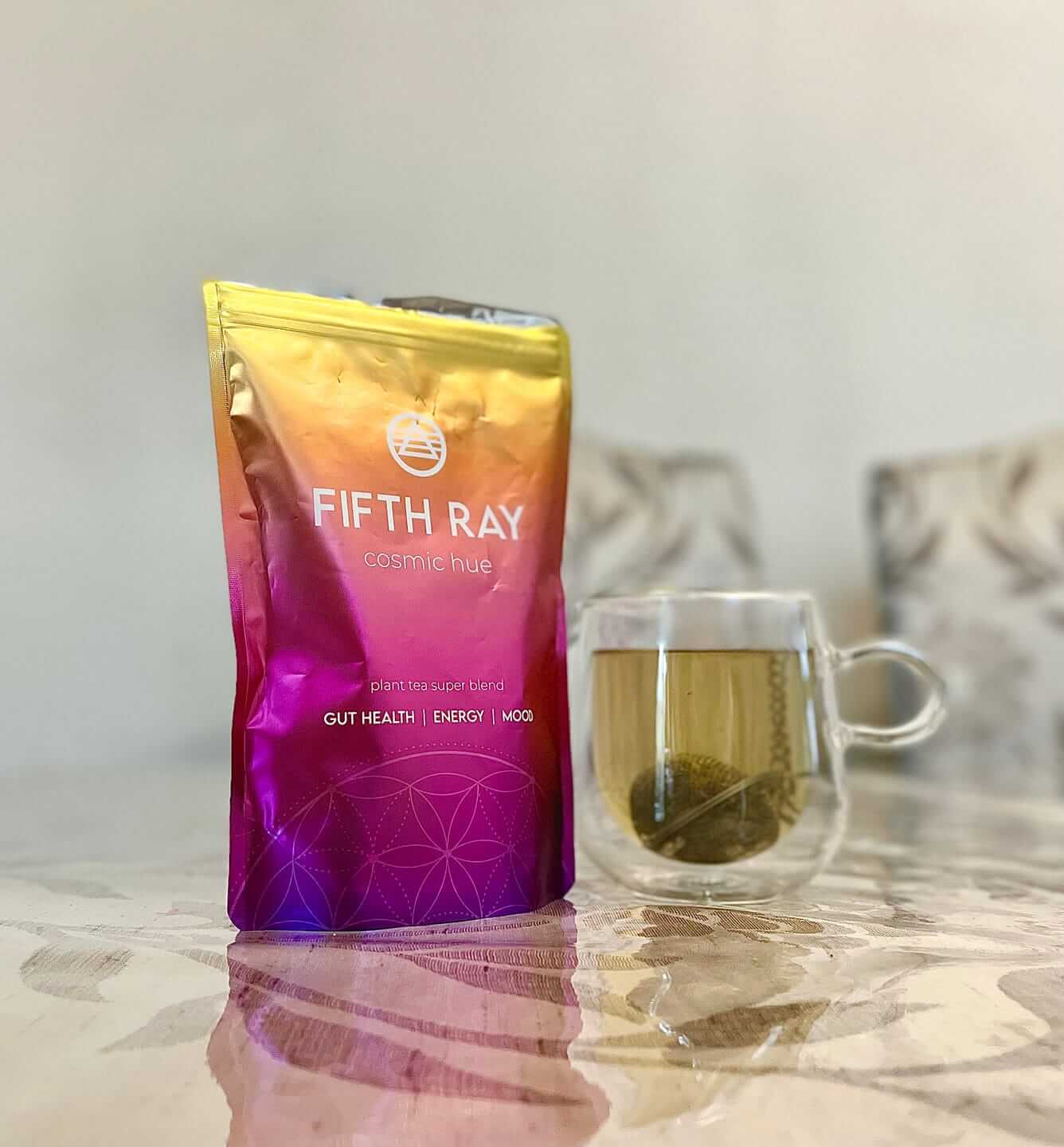 Colorful tea package beside a glass cup of tea on a table.