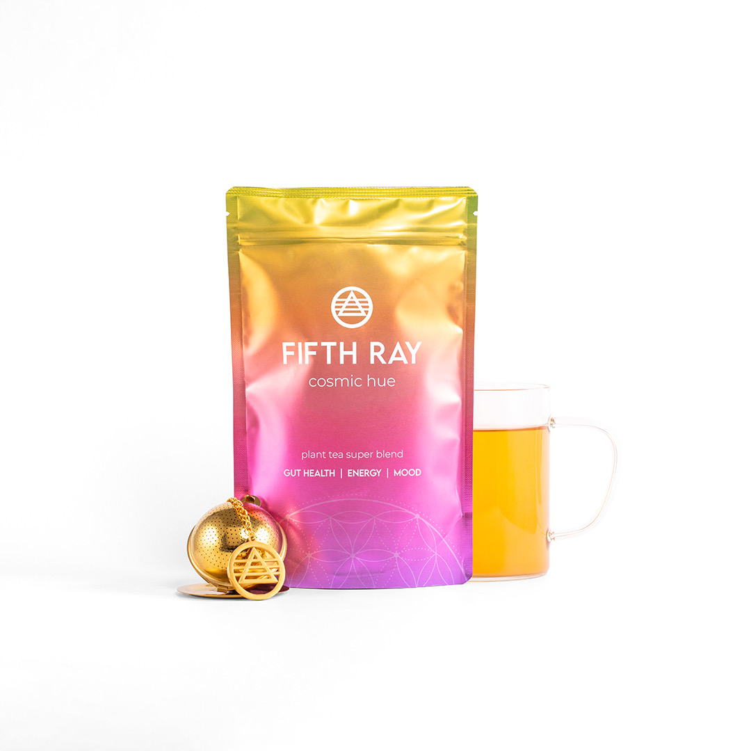 A pouch of Fifth Ray tea next to a gold tea infuser and a mug of tea.