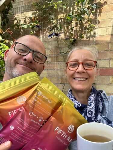 Two people holding coffee bags and a cup, smiling outdoors.