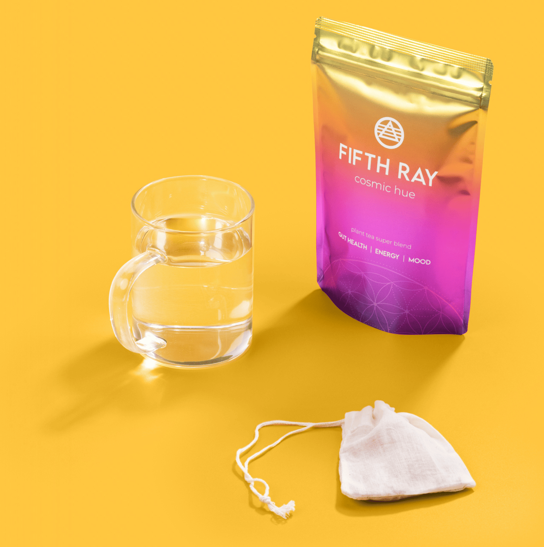 Glass of water, tea bag, and colorful tea package on yellow background.