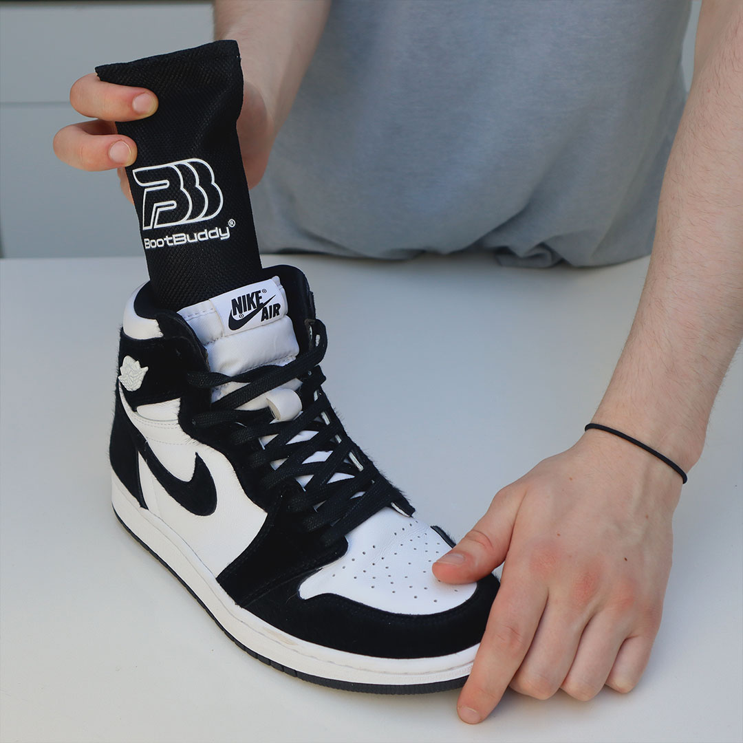 Person inserting BootBuddy into a black and white Nike Air shoe.