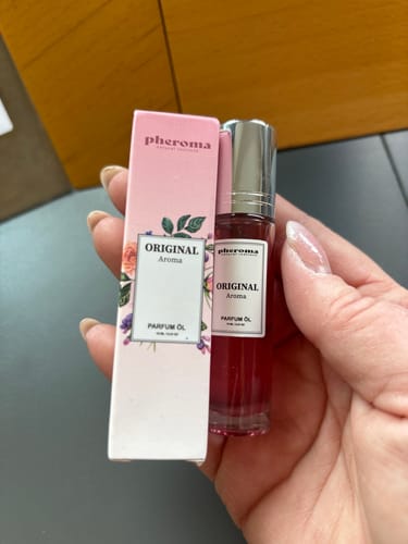 Hand holding a pink perfume box and bottle labeled 'Original Aroma'.