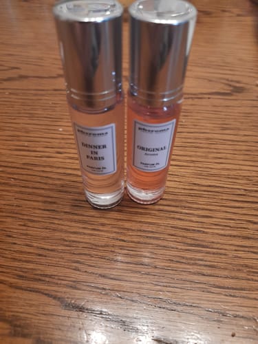 Two small perfume bottles with silver caps on a wooden surface.