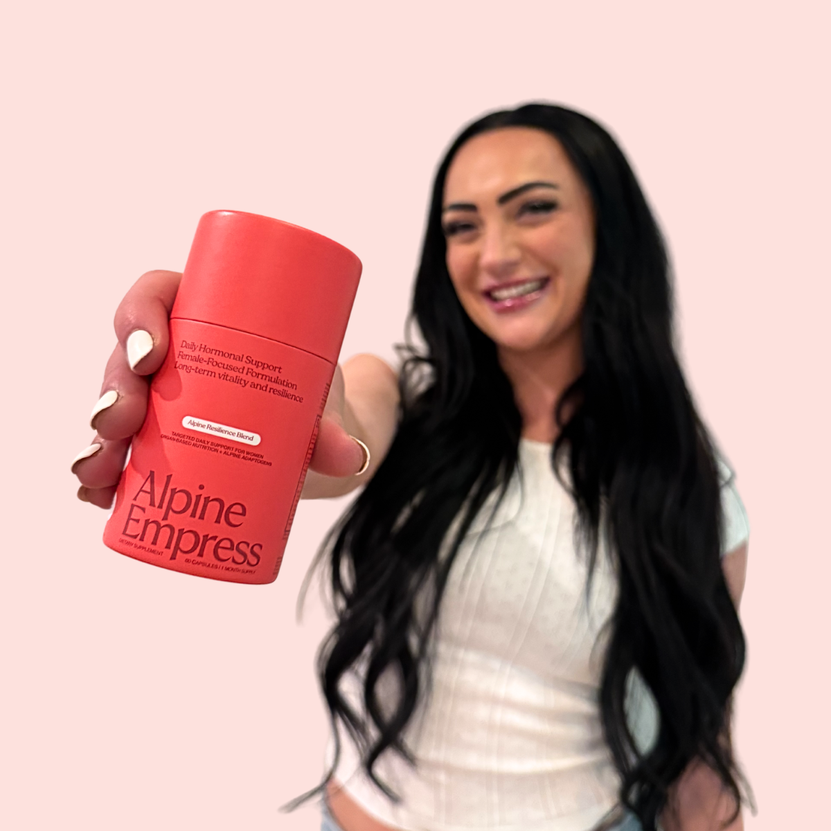 A smiling woman holds a red bottle of Alpine Empress supplement toward the camera, with the product in focus.