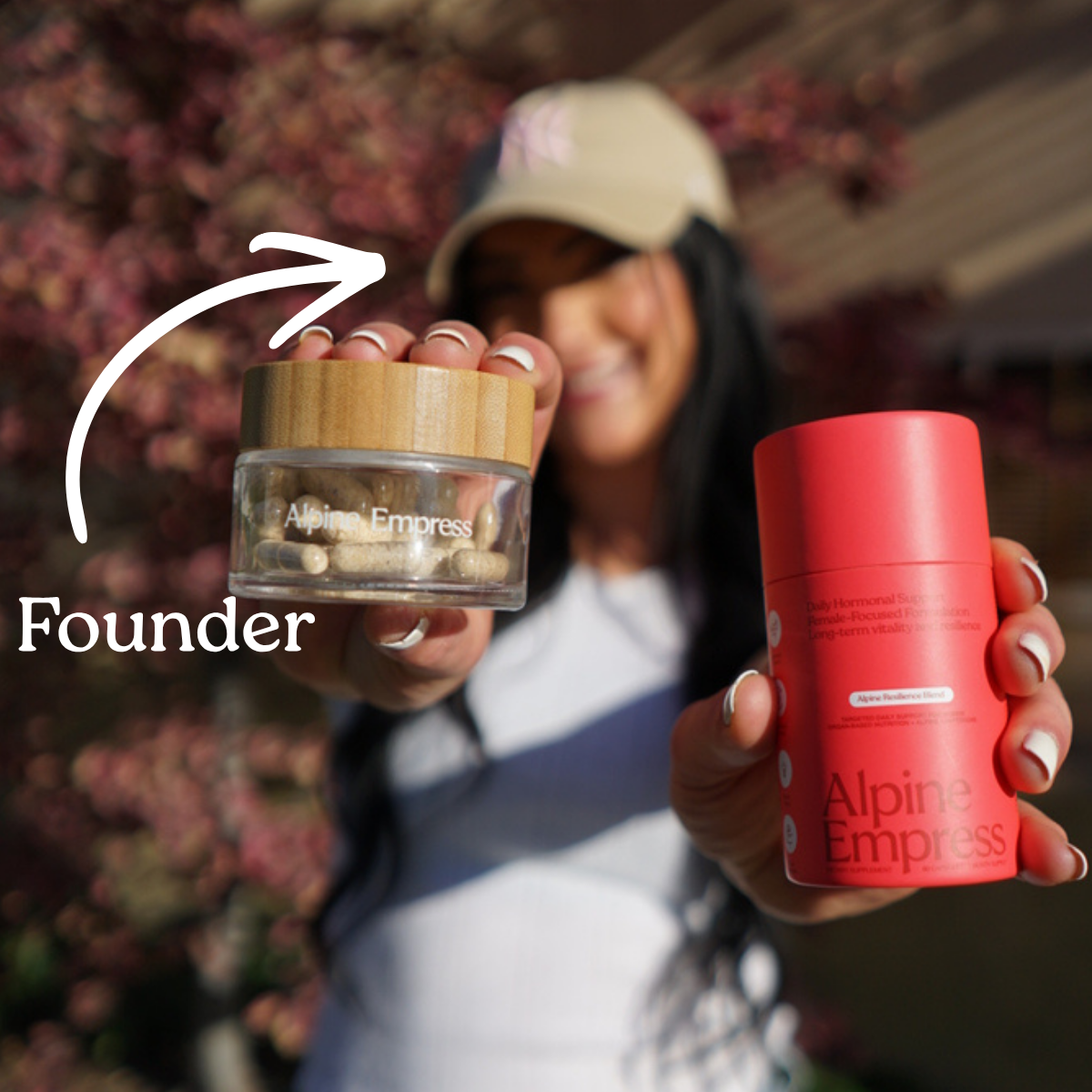 The founder of Alpine Empress holding a clear jar of capsules and a red container of supplements.