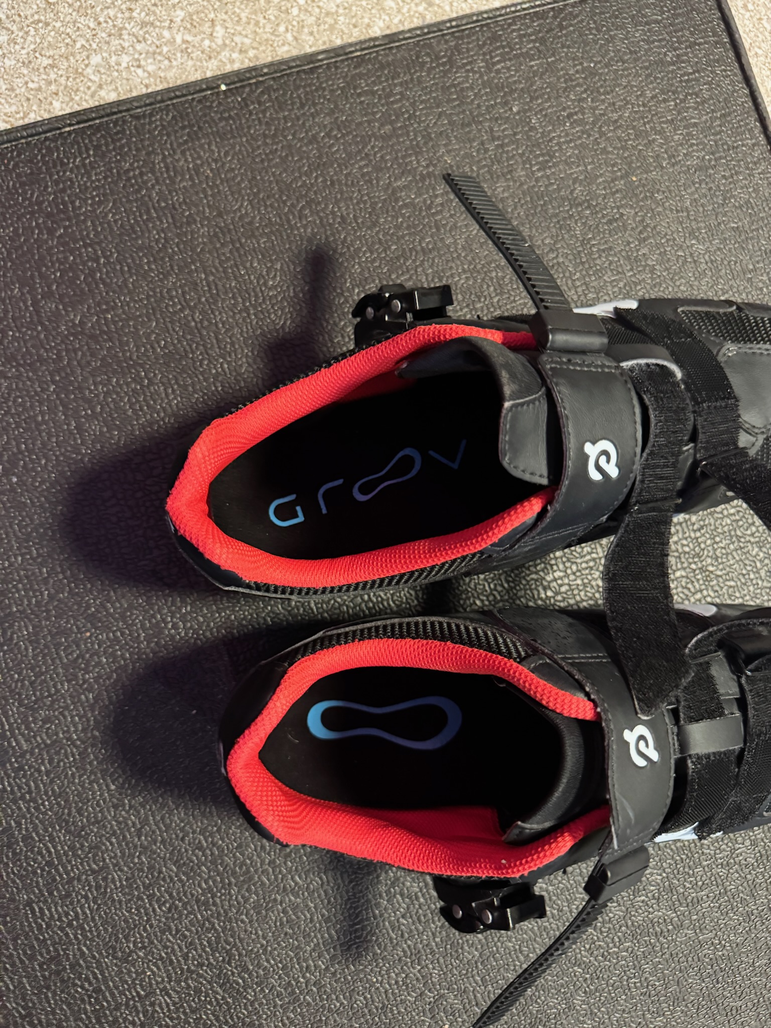 Top view of black and red cycling shoes on a dark surface.