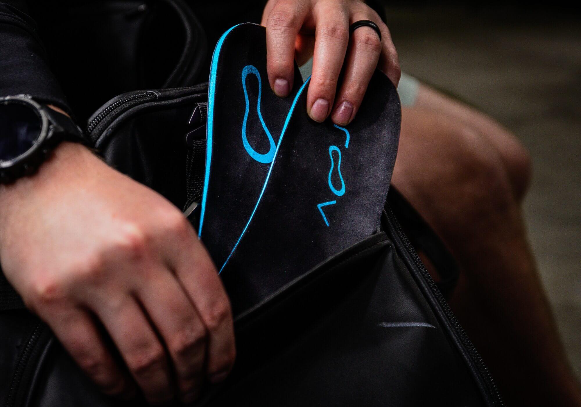 Person placing insoles into a black bag.