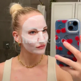 Person taking a selfie wearing a white face mask in a bathroom.