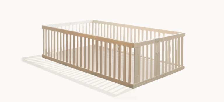 A light-colored, rectangular wooden baby crib with slats, shown on a plain white background.