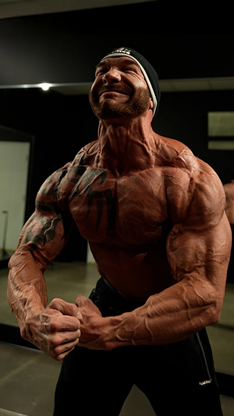 A muscular person flexing intensely in a gym setting.