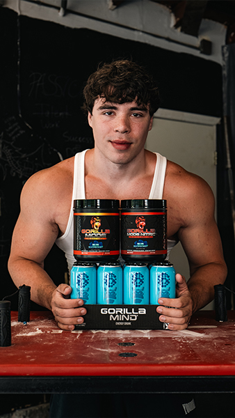 Person in a gym holding Gorilla Mind supplements on a table.